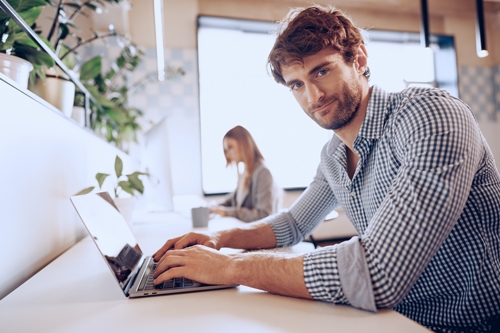 young bearded successful businessman working laptop office with female colleague
